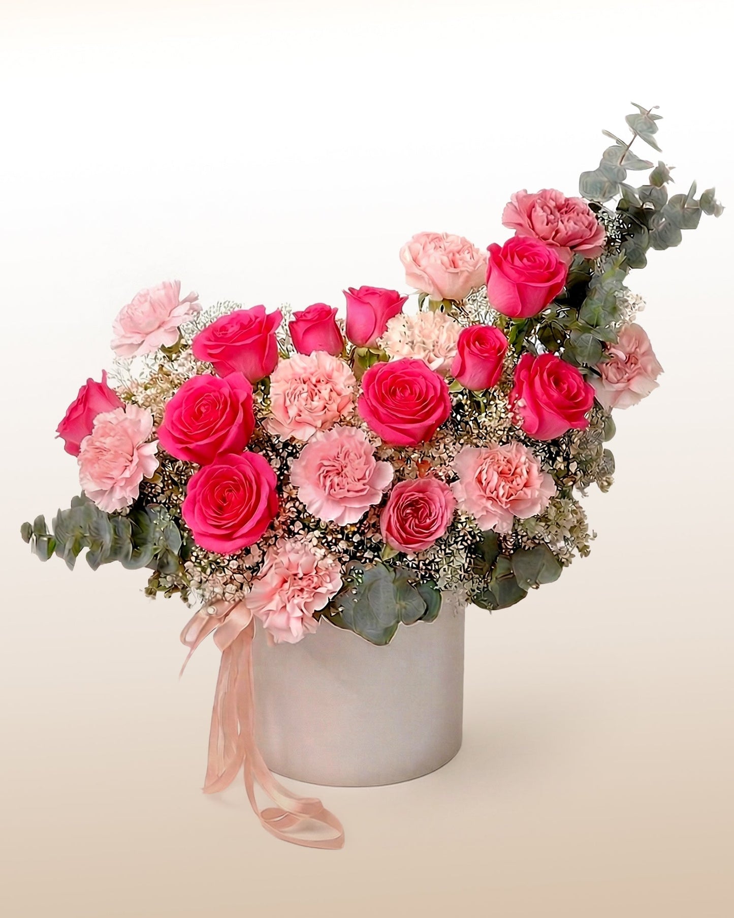 Rosas fucsia y claveles en caja cilíndrica. Un arreglo de alto impacto para decirlo sin vueltas. Envío a domicilio.