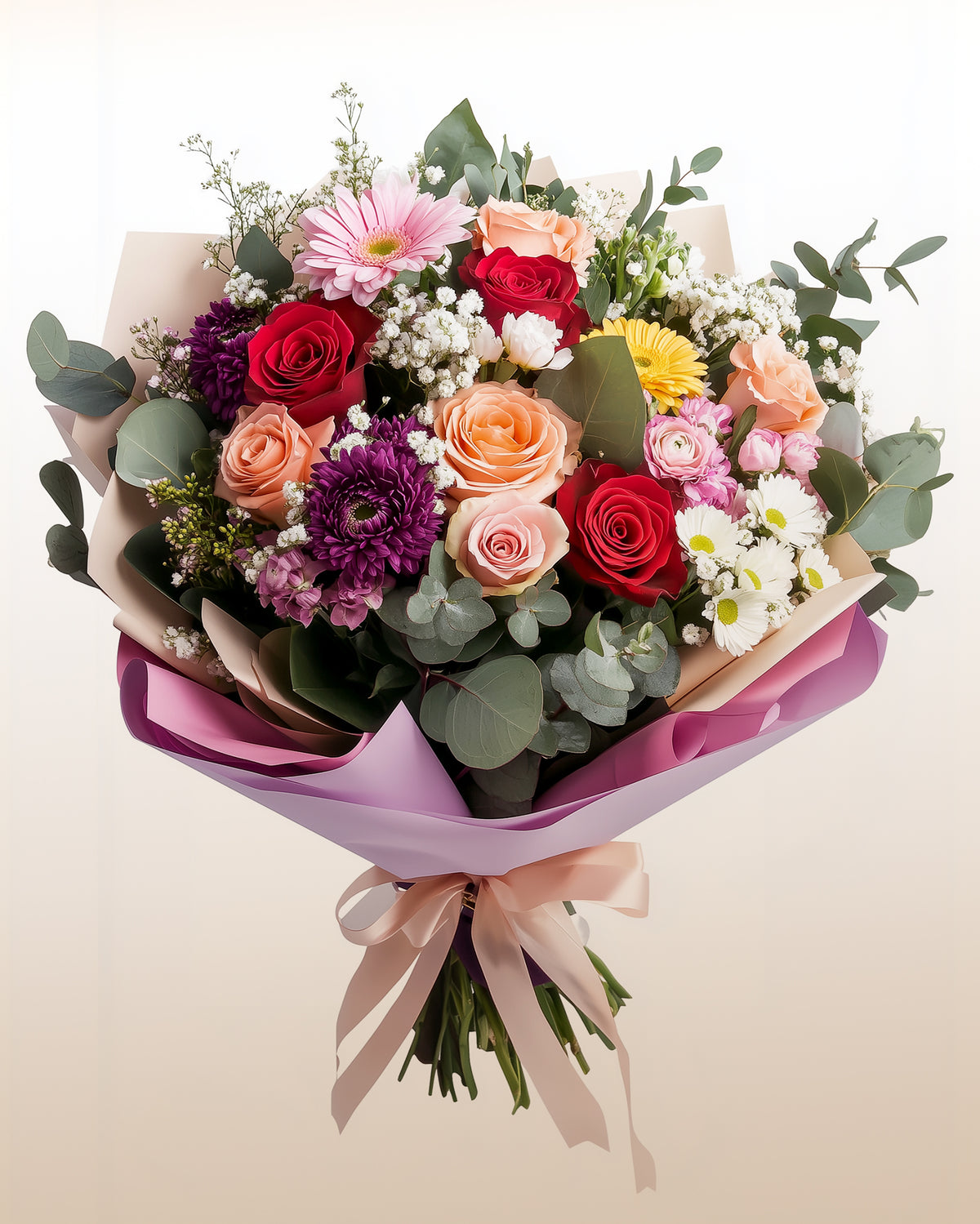 Ramo atado a mano de rosas rojas, durazno y rosadas con gerberas, crisantemos morados, margaritas, gypsophila y eucalipto, envuelto en papel rosa
