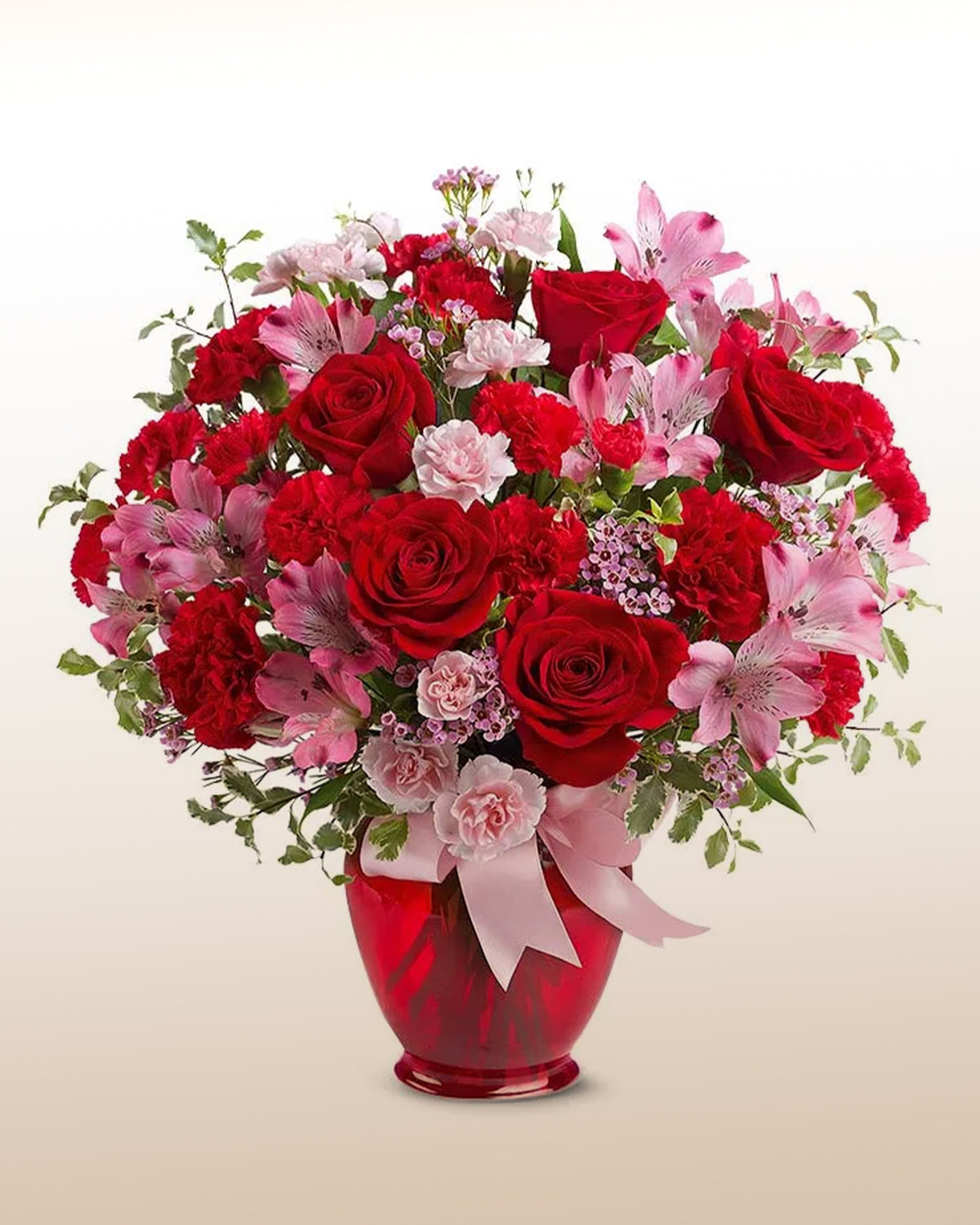 Arreglo de rosas rojas con claveles y astromelias rosadas en florero de vidrio rojo con moño rosado